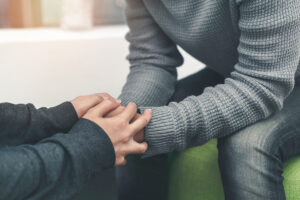 Two people hold hands as they discuss importance of depression treatment
