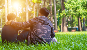 Two friends sit in grass and talk about how to heal from trauma