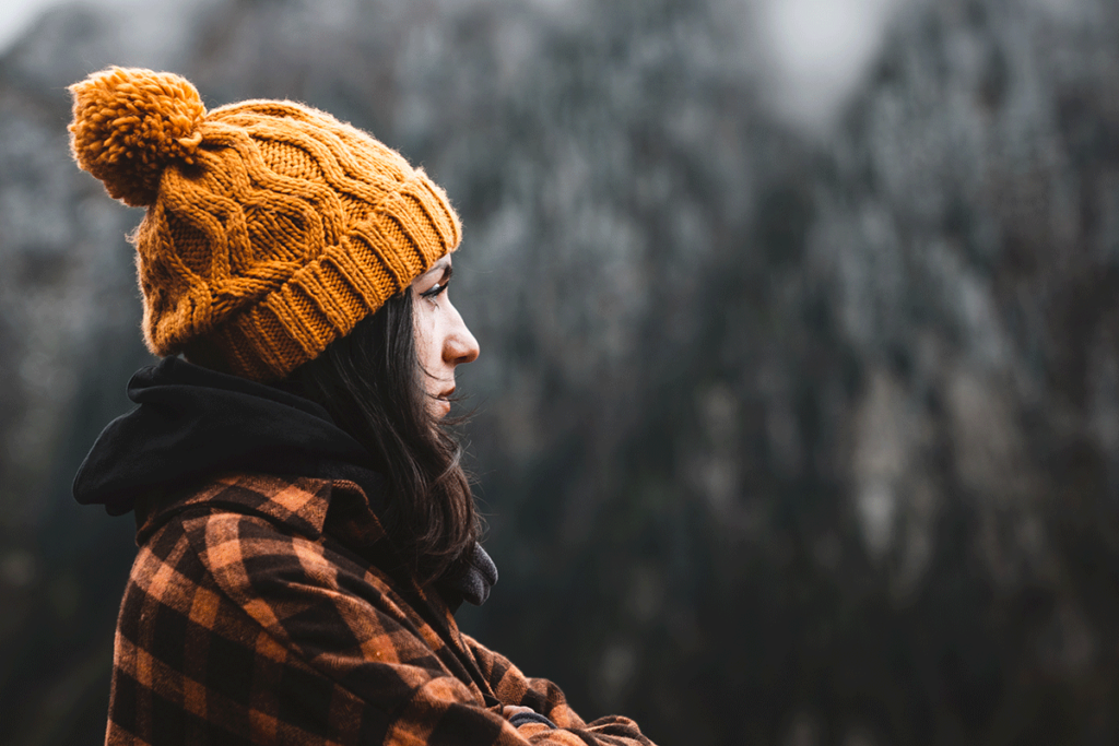 Woman in flannel and winter hat stands outside wondering how to cope with seasonal depression