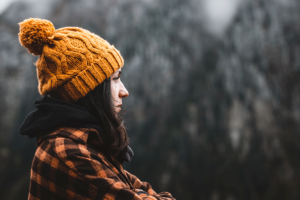 Woman in flannel and winter hat stands outside wondering how to cope with seasonal depression